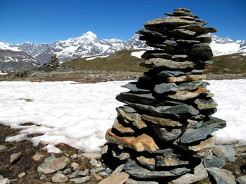 Stack of rocks on frozen lake against sky