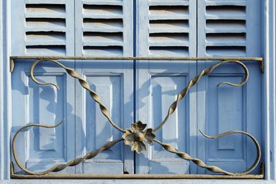 Close-up of closed metal fence against blue wall