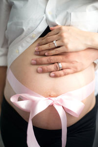 Couple touching pregnant wife abdomen tied with ribbon