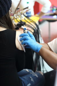 Cropped hands of artist making tattoo on female customer