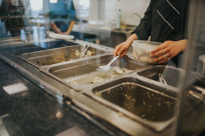 Midsection of woman packing food in container at restaurant