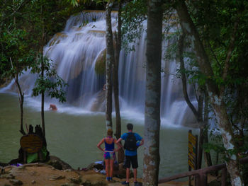 Rear view of man standing by waterfall