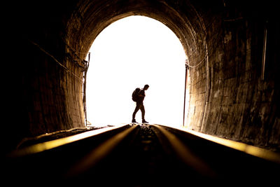 Backpacker man walking on railway in tunnel