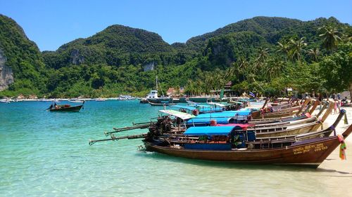 Boats moored in sea against mountains