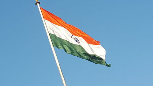 Low angle view of flag against clear blue sky