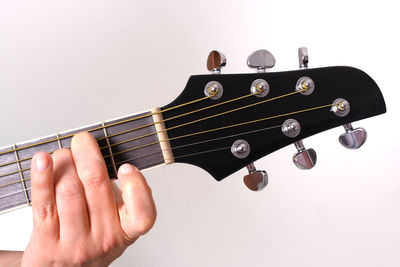 Close-up of hand playing guitar against white background
