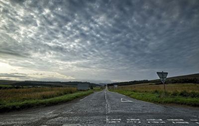 Road amidst field against sky