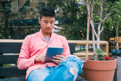 Young man using mobile phone while sitting outdoors