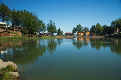 Scenic view of lake by trees and buildings against sky