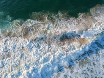 Drone view of beautiful turquiose sea waves breaking on sandy coastline. aerial shot of golden beach