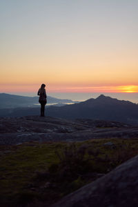 Man standing on mountain against sky during sunset