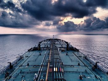 High angle view of container ship sailing on sea against cloudy sky