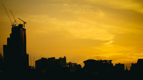 Silhouette buildings against dramatic sky during sunset