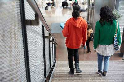 Rear view of female friends moving down on steps in university