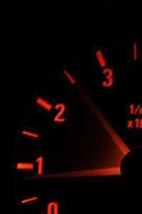 Close-up of illuminated clock tower seen through car windshield