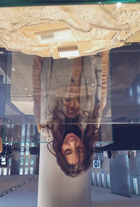 Portrait of smiling young woman standing against ceiling