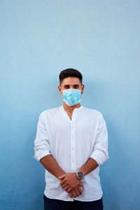 Young latin man with mask on blue background