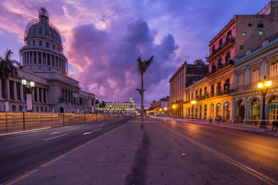 Illuminated street by el capitolio against sky