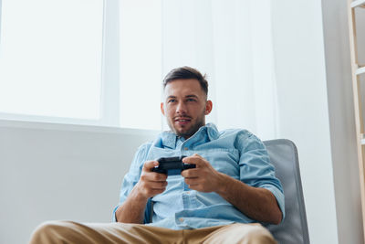 Portrait of young man using mobile phone while sitting on sofa at home