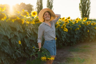 Beautiful young woman with sunflowers enjoying nature and laughing on summer sunflower field.