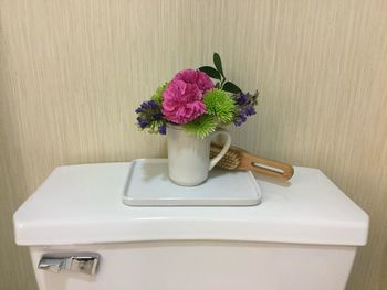 Flower vase and brush on flush tank against wall