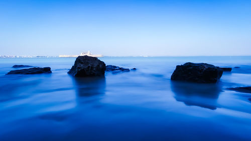 Rocks in sea against blue sky