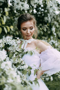 A beautiful delicate elegant woman bride in a wedding dress walks alone in a spring outdoor park