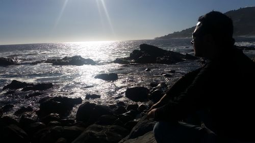 Rear view of silhouette woman standing on beach against clear sky