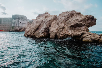 Rock formations by sea against sky