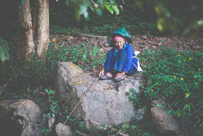 Full length of woman sitting on land in forest