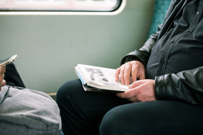 Midsection of man sitting in train