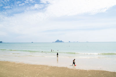 People standing on beach against sky