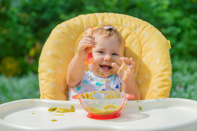 Cute baby girl eating food on table