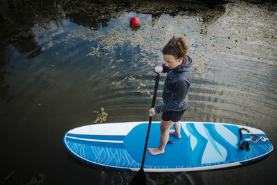 Woman paddleboarding, boats inn background barefoot