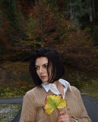 Young woman looking away while standing by plants