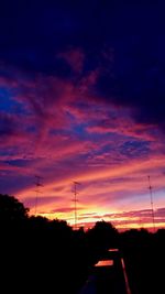 Silhouette trees against dramatic sky during sunset