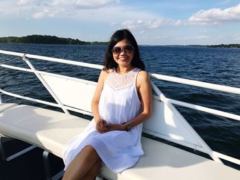 Portrait of smiling woman sitting in boat against sky