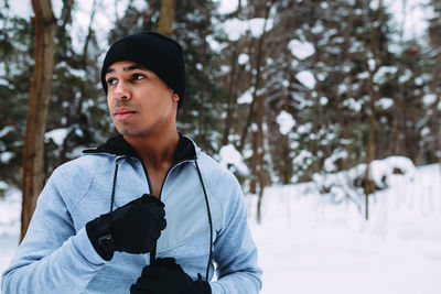 Young man in warm clothing looking away during winter