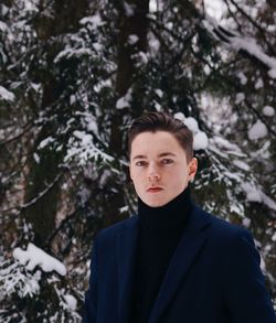 Portrait of young man standing against frozen trees