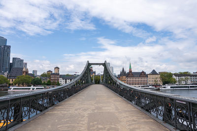 Bridge over river in city against sky