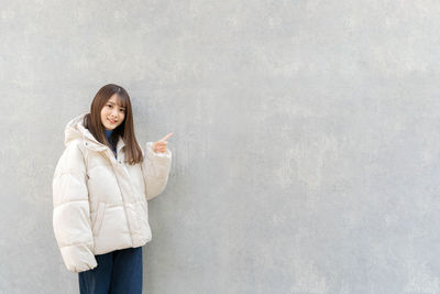 Young woman standing against wall