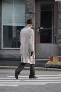 Rear view of man walking on sidewalk