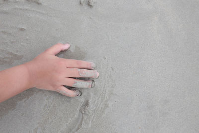 High angle view of woman hand on sand at beach