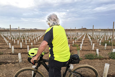 Rear view of man riding bicycle on field