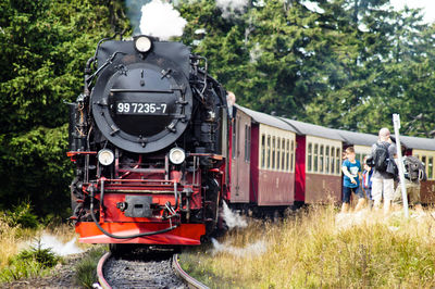 Steam train moving on track against trees