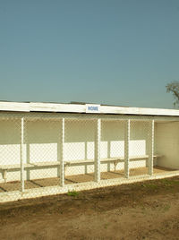 Text on fence against clear blue sky