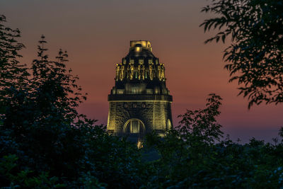 Low angle view of illuminated building against sky at sunset