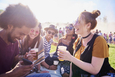 Friends holding beer in glasses while standing on grass