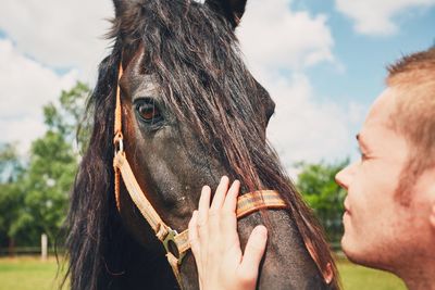 Close-up of man stroking horse on sunny day