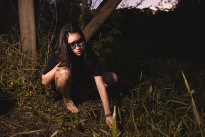 Young woman crouching by plant